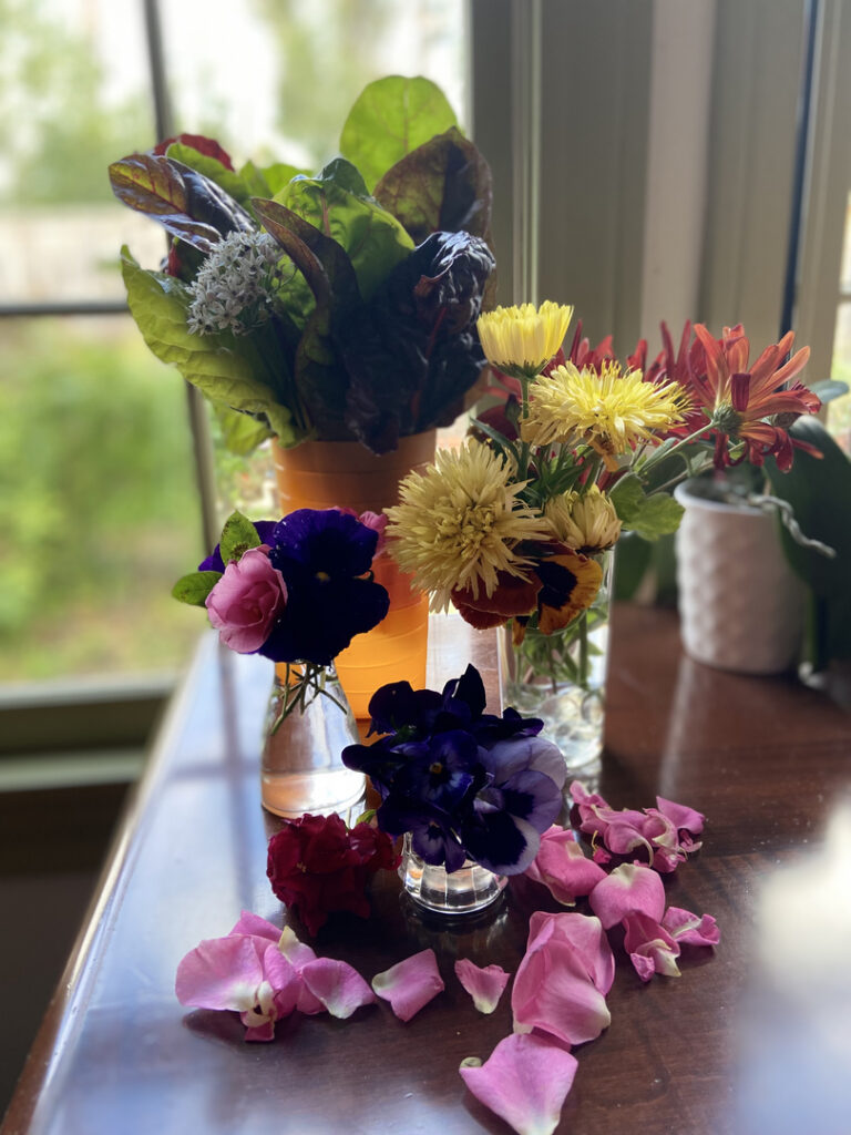 A vibrant floral arrangement with diverse colorful flowers on a wooden table.